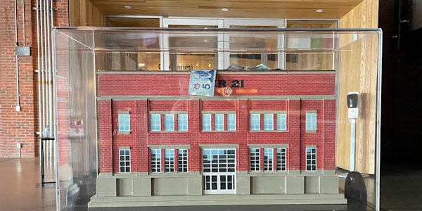 
A plexiglass donation box with a miniature edition of the Pier 21 building inside of it.
