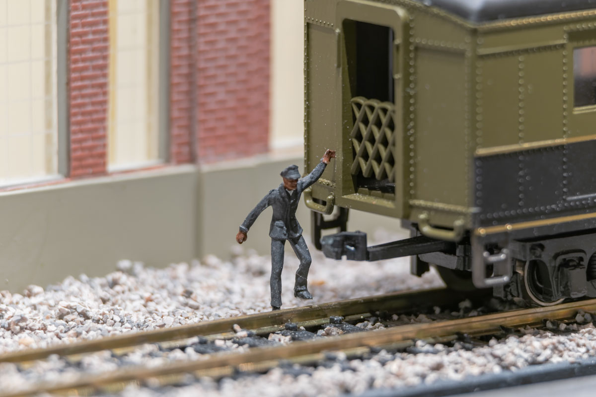 A model figurine of a dark-skinned man with his hand on a railway car.